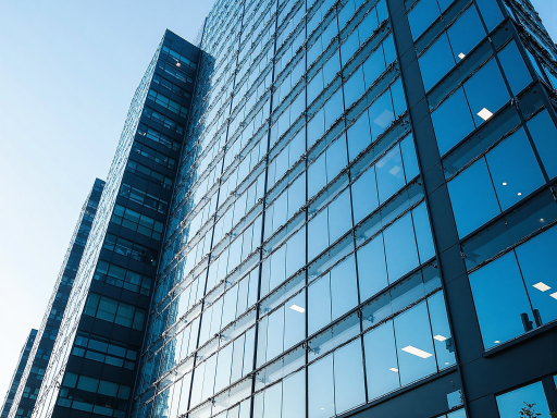 Modern office building exterior with glass facade and green landscaping in urban environment during daylight hours